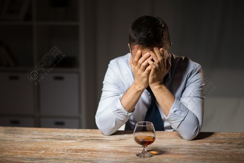 酒精中毒酒精成瘾和人们观念晚上在桌上的男性酒精饮用的白兰地酒杯酒