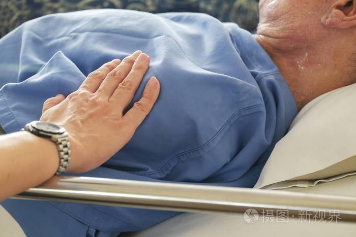 妇女感动和祈祷生病的老人在医院