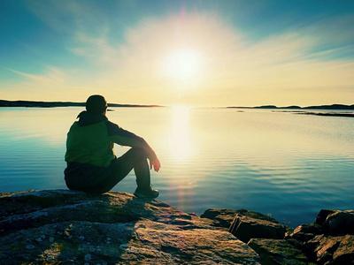 海边男生孤独孤独的徒步旅行者独自一人坐在海边享受日落.