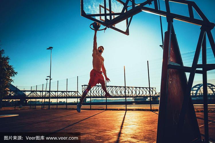 日落时分,街头篮球运动员在球场上表演扣篮