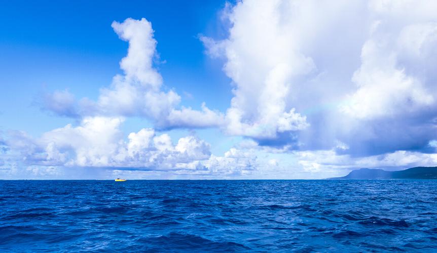 在一望无际的大海之上一叶孤舟在漂泊深蓝色大海之上有彩虹